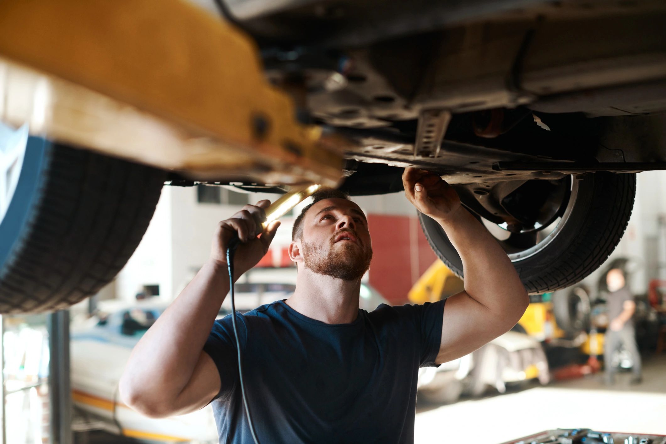 Automotive technician working under a lifted vehicle